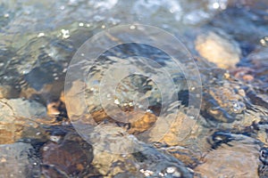 Flowing river water surface with big stone closeup
