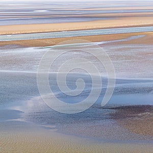 Flowing sea water on sand at low tide in the bay of Mont Saint-Michel