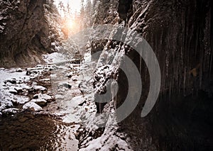 Flowing small creek running out icicle cave and washing big boulders. First sun rays lite young snow islands. Cold early winter