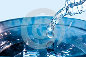 A flowing stream of blue water.A stream of blue water pours from the neck of a glass bottle.Frozen water drop photographed at high