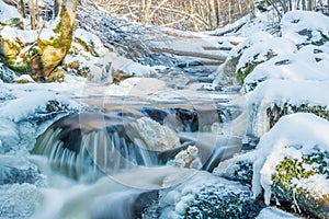 Flowing stream in winter. Ice on stones.