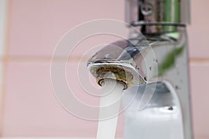 Flowing tap water run from corrosive steel spigot, flow on pink backdrop. Plumbing, bathroom apparatus and water flood