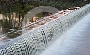 Flowing water cascading over a weir on yorkshire river