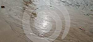 Flowing water mark on beach sand with sunlight reflection