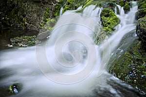 Flowing water in waterfall between rocky stream in the mountains