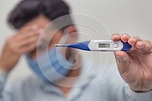 Flu and corona concept: Man is holding a fever thermometer in his hand