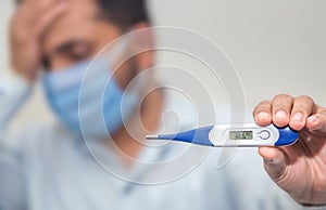 Flu and corona concept: Man is holding a fever thermometer in his hand