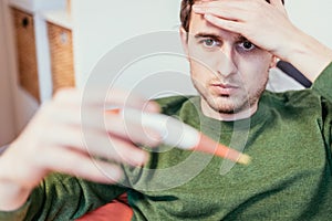 Flu and corona concept: Man is holding a fever thermometer in his hand, close up