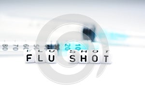 Flu shot text spelled with tiled letters standing next to a syringe