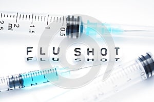 Flu shot text spelled with tiled letters standing next to a syringe