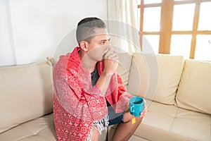 Flu-sick man sitting on the couch at home. Concept of medicine