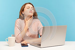 Flu-sick young woman employee sitting at workplace with laptop and holding painful neck, suffering sore throat