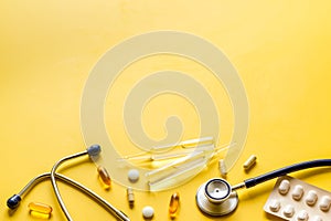 Flu treatment - pills and stethoscope on yelllow table copy space