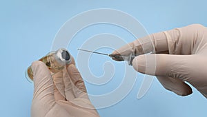 Flu or virus vaccine bottle and syringe in doctor or scientist hands on blue background. Medicine vial dose injection for vaccinat