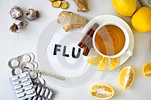FLU - written on piece of paper among the products for the treatment of common cold - lemon, ginger, chamomile tea pills. Natural