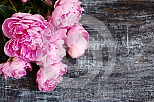 Fluffy bouquet of pink fresh peony flowers on scratched shabby dark wood