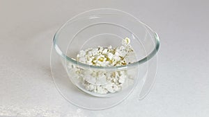 Fluffy bright pieces of popcorn falling in slow motion against a white background and falling into a bowl