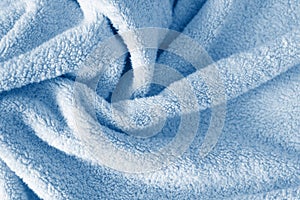 Fluffy classic blue towel background, close-up. Gentle baby pastel fabric with waves and folds. Folded tender light blue towel