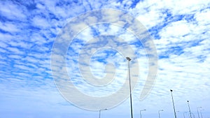 Fluffy clouds in the blue sky and the light pole lined