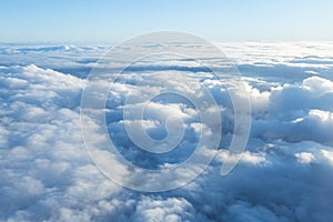 Fluffy clouds seen from above from the airplane window. .Climatology and weather concept