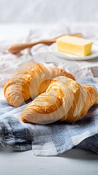 Fluffy croissants with butter on napkin, breakfast setting with clear upper space