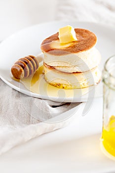 Fluffy Japan souffle pancakes, hotcakes with butter and maple syrup or honey sauces on light white background