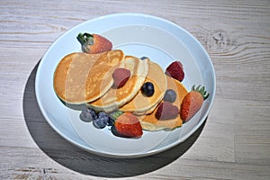 Fluffy japanese pancakes with berries isolated on white wooden table.