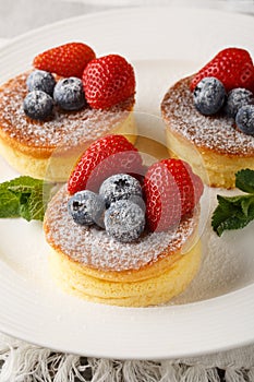 Fluffy Japanese Souffle Pancakes are like eating cottony clouds with fresh berries close-up on a plate. Vertical