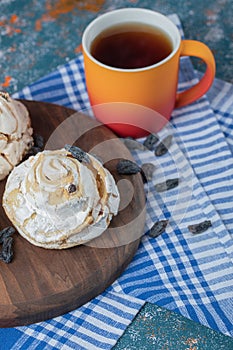 Fluffy meringue muffins with black dry grapes on the table with a cup of tea