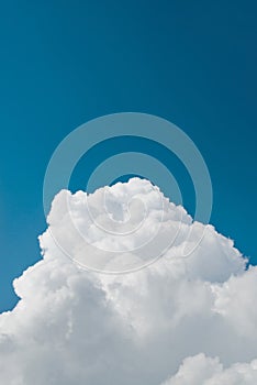 Fluffy soft white clouds on blue clear sky outdoors on sunny summer day. Vertical image, copy space