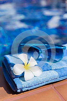 Fluffy towel with sunglasses and flower pool