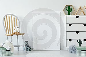 Fluffy toy placed on wooden chair in white baby room interior wi