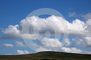 Fluffy white clouds blue sky over moorland skyline