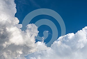 Fluffy white clouds in dark blue sky. clear open space in the atmosphere. color of clouds low angle view look up to the blue clear