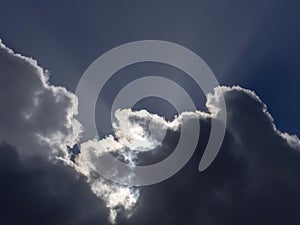 Fluffy white cumulus clouds with silver lining and sun rays. Weather or concept, metaphor.