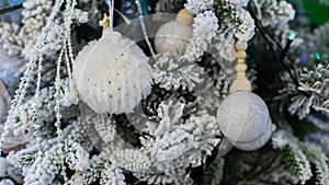 Fluffy white fur ball on a Christmas tree with artificial snow. New Year card background backdrop