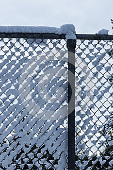 Fluffy white snow collected in a chain link fence