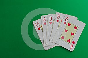 Flush of hearts cards of a poker deck over a green background