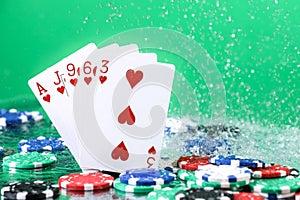 Flush poker combination under the water drops and falling poker chips against green background. Online gambling. Betting.