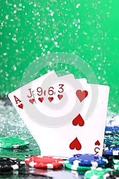 Flush poker combination under the water drops and falling poker chips against green background. Online gambling. Betting. Gambling