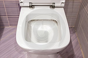 Flush in the toilet. Clean white toilet flushes water, closeup photo. photo