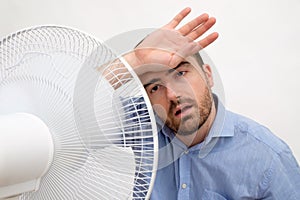 Flushed man feeling hot in front of a fan