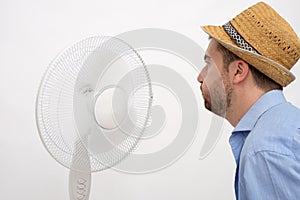 Flushed man feeling hot in front of a fan