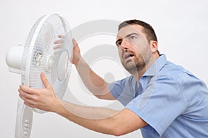 Flushed man feeling hot in front of a fan