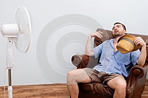 Flushed man feeling hot in front of a fan