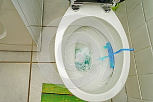 flushing water toilet wc seat with foam with blue scented stones as scent rinser and opened seat white tiles floor