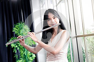 Flute classical instrument profestional player playing song.  A young and elegant Asian woman plays the flute