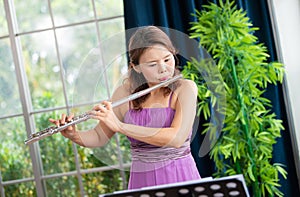 Flute classical instrument profestional player playing song.  A young and elegant Asian woman plays the flute