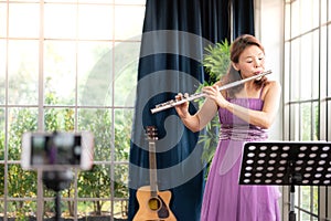 Flute classical instrument profestional player playing song.  A young and elegant Asian woman plays the flute