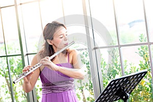 Flute classical instrument profestional player playing song.  A young and elegant Asian woman plays the flute